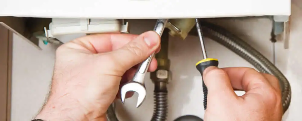 Boiler repair technician tightening pipe fittings and connections in Burlington, VT