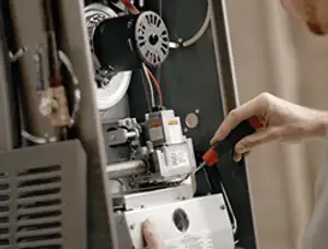 Furnace repair technician inspecting internal components and wiring in Burlington, VT