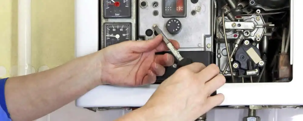 Heating repair technician adjusting boiler controls and components in Burlington, VT