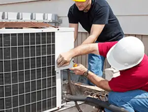 HVAC technicians repairing an outdoor AC unit on a rooftop in Burlington, VT