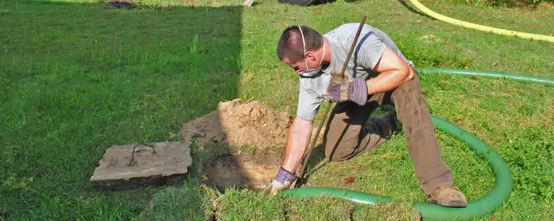 Septic pumping technician servicing a residential septic tank in Burlington, VT