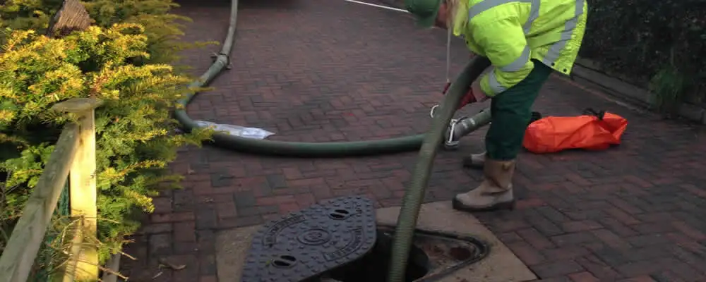 Septic tank cleaning technician servicing a septic tank with a vacuum hose in Burlington, VT