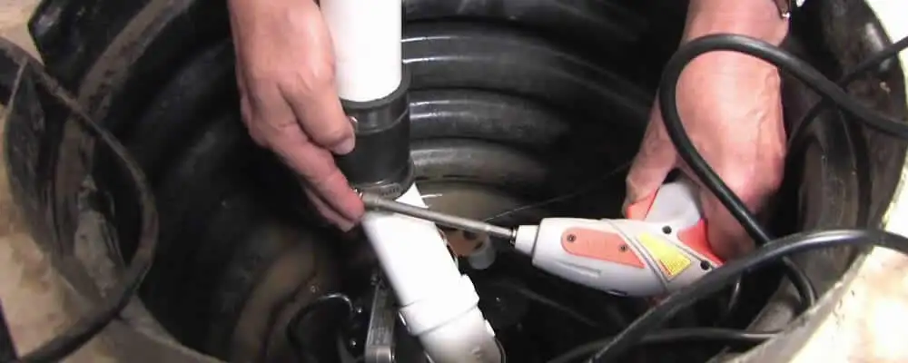 Sump pump installation technician connecting PVC discharge piping in Burlington, VT