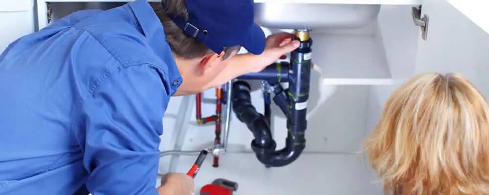 Plumber repairing under-sink drain pipes and fittings in Burlington, VT